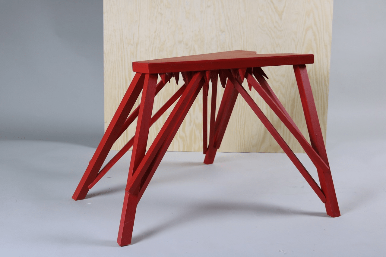 picture of red wooden stool with spikes underneath